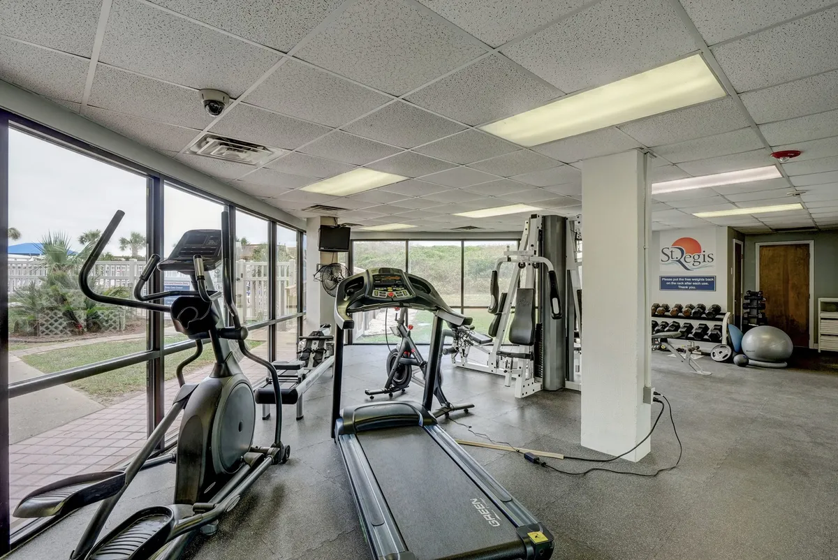 A modern fitness center with treadmills, elliptical machines, weight training equipment, and large windows letting in natural light. The space feels energetic and motivational, ideal for maintaining a healthy lifestyle.