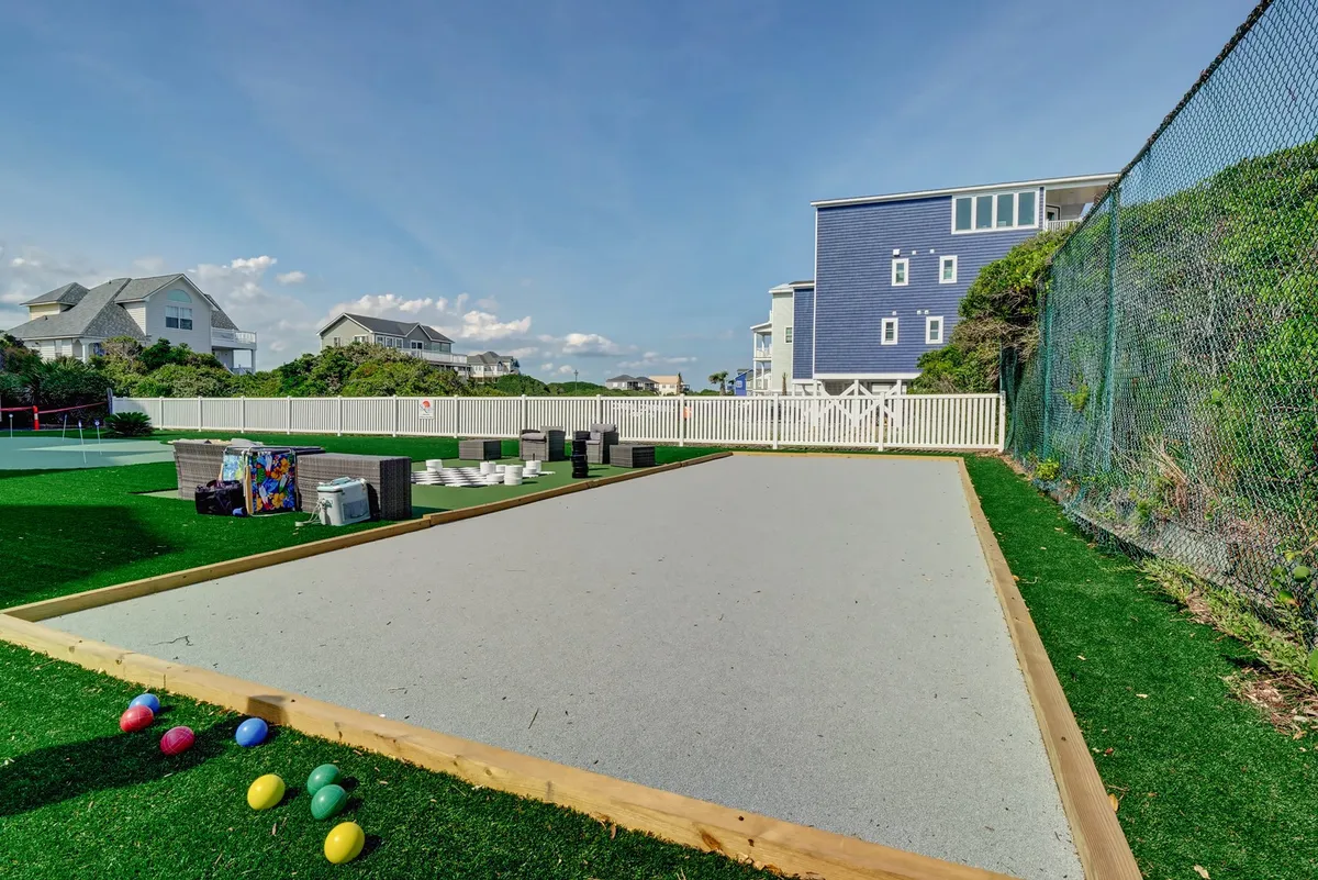 A vibrant bocce ball court set in a spacious green area, with colorful bocce balls ready for play. The surrounding green space offers a playful, communal environment for outdoor activities and gatherings.