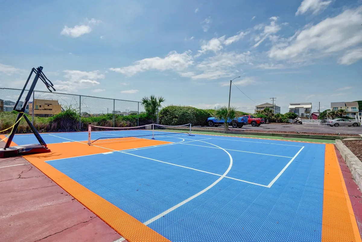 An energetic outdoor court featuring a basketball hoop, tennis net, and a colorful court surface, inviting groups to engage in friendly competitions and active play.