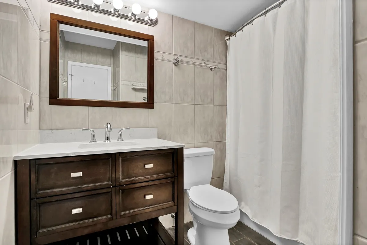 A bright and calming bathroom with a vanity, sink, large mirror, and shower curtain, creating a refreshing environment for personal grooming or relaxation after a long day.